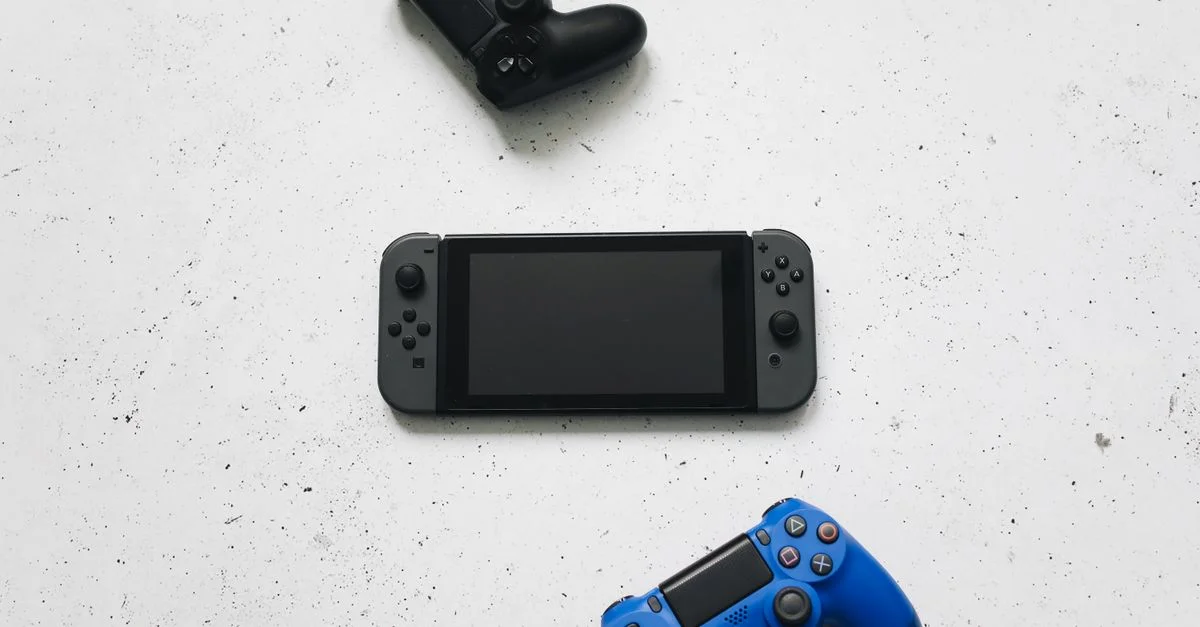 Vue de dessus de consoles de jeux et manettes sur une surface blanche, présentant des dispositifs de jeu populaires.